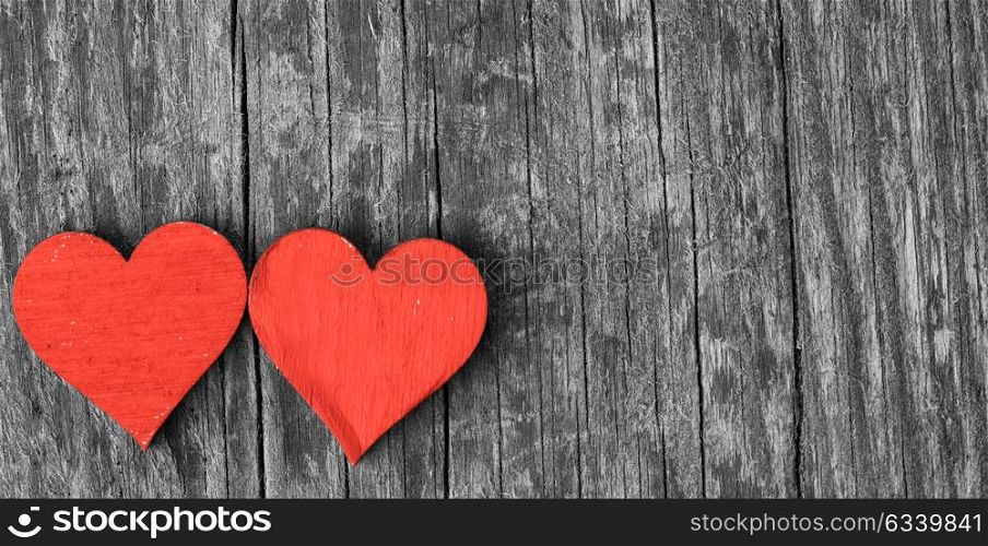 Two wooden hearts. Two small wooden red hearts on old cracked wood background