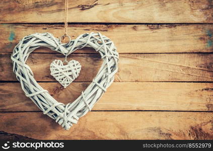 Two wooden rustic decorative hearts hanging on vintage wooden background with space.