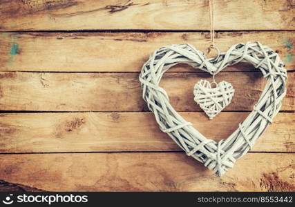 Two wooden rustic decorative hearts hanging on vintage wooden background with space.