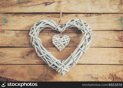 Two wooden rustic decorative hearts hanging on vintage wooden background with space.