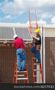 Two workers installing solar panels on the side of a building. Vertical with room for text.