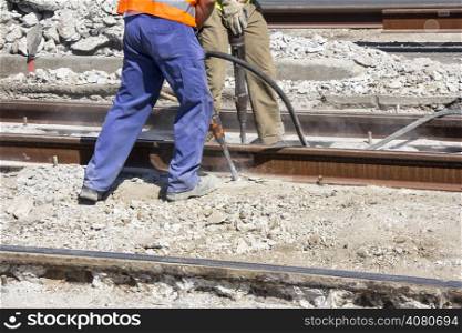 Two Workers with pneumatic hammer drill equipment breaking Concrete at construction site