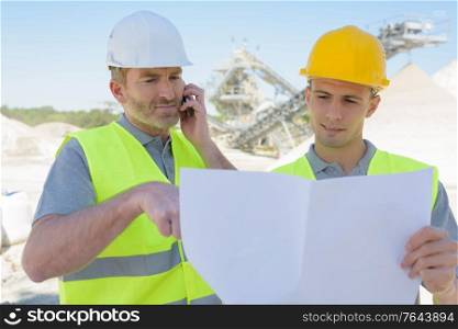 two workmen discussing project plans in factory