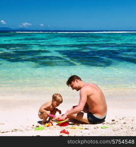 Two year old baby boy and his father playing on beach at Seychelles