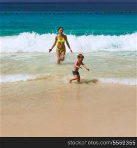 Two year old baby boy and his mother playing on beach at Seychelles