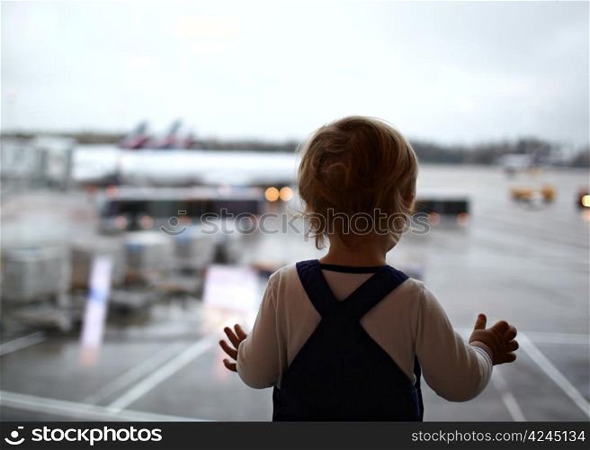 Two year old babyboy is looking at the planes in the airport.