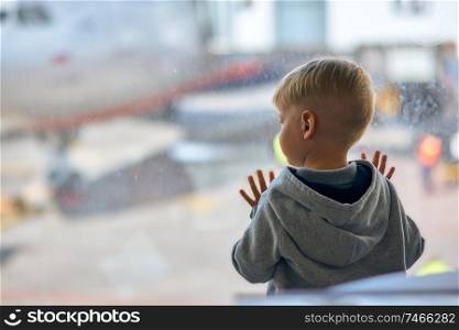 Two year old boy at the airport looking at plane