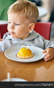 Two year old boy eating dessert in cafe