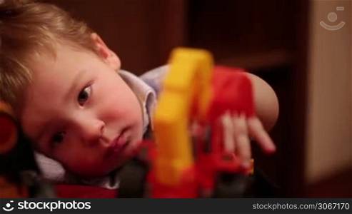 Two year old boy plays with toy trucks. Close up shot.