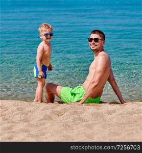 Two year old toddler boy on beach with father 