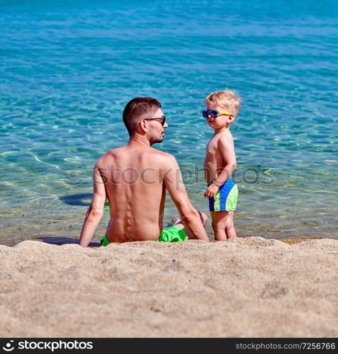 Two year old toddler boy on beach with father 