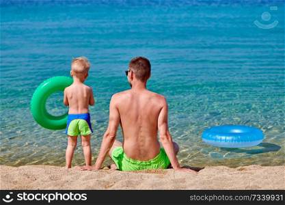 Two year old toddler boy on beach with father 
