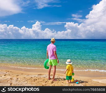 Two year old toddler boy on beach with father, holding inflatable ring. Summer family vacation. Sithonia, Greece. 