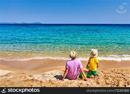 Two year old toddler boy on beach with father. Inflatable ring and beach toys. Summer family vacation. Sithonia, Greece. 