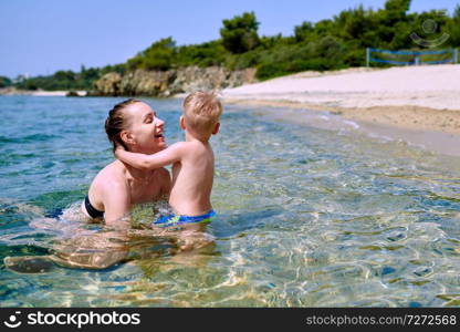 Two year old toddler boy on beach with mother 