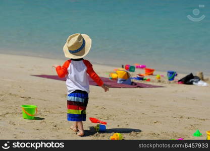 Two year old toddler boy playing with beach toys on beach