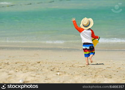 Two year old toddler boy playing with beach toys on beach