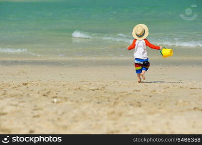 Two year old toddler boy playing with beach toys on beach