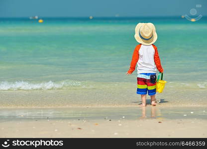 Two year old toddler boy playing with beach toys on beach