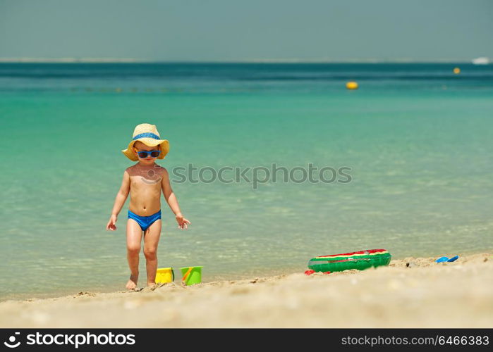 Two year old toddler boy playing with beach toys on beach