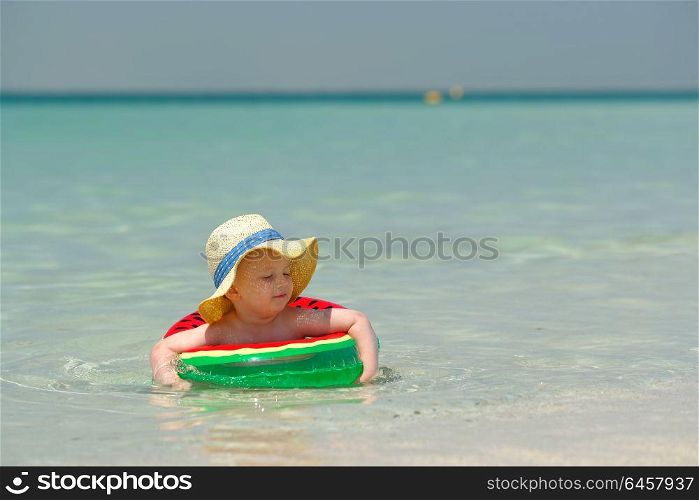 Two year old toddler boy with inflatable swim ring on beach