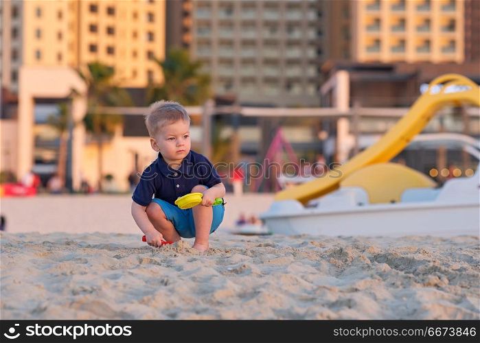 Two year old toddler playing on beach. Two year old toddler boy playing with beach toys on beach