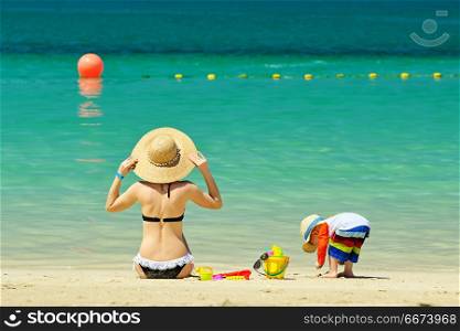 Two year old toddler playing with mother on beach. Two year old toddler boy playing with beach toys with mother on beach