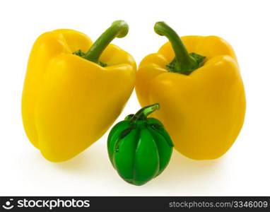 Two yellow bell pepper together with small green glass bell pepper ornament, isolated on white background