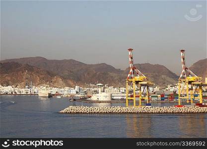 two yellow cranes in shipping port near mountains summer day