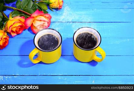 Two yellow cups of coffee on a blue wooden background, top view. Two yellow cups of coffee