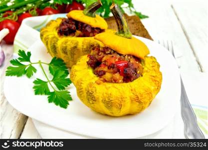 Two yellow squash stuffed with meat, tomatoes and peppers in the dish, bread, garlic, parsley and fork on the background light wooden boards