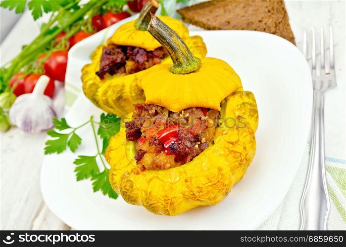 Two yellow squash stuffed with meat, tomatoes and peppers in the dish, bread, garlic, parsley and a napkin on the background light wooden boards