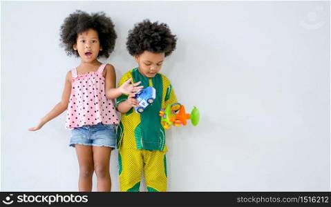Two young african boy and girl stand in front of white background with different action