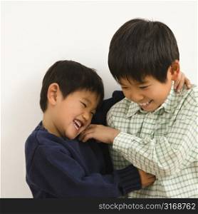 Two young Asian brothers playing and laughing.