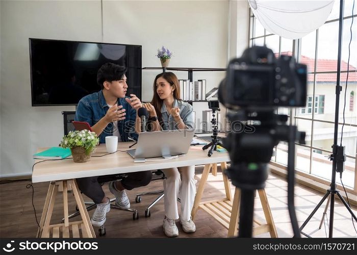 Two young Asian vlogger using video online live streaming and broadcasting. Happy couple of bloggers recording a video to live in social networks.