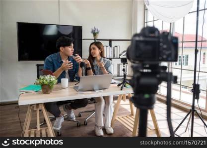 Two young Asian vlogger using video online live streaming and broadcasting. Happy couple of bloggers recording a video to live in social networks.