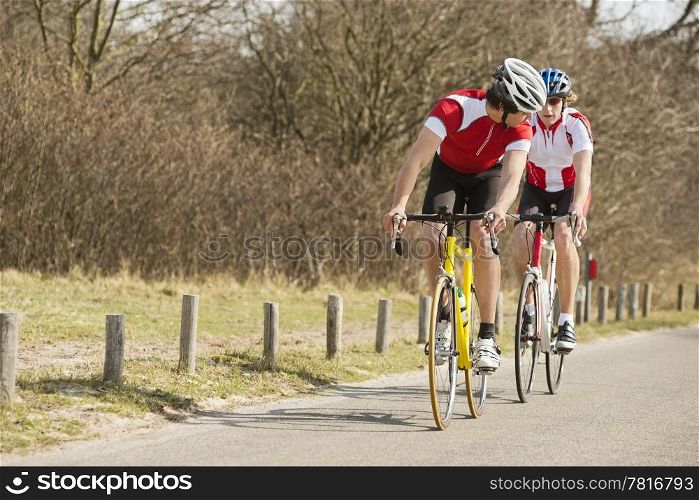 Two young athlete riding bicycles on a country road