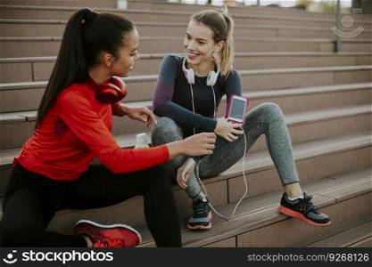Two young attractive female runner taking break after jogging outdoors