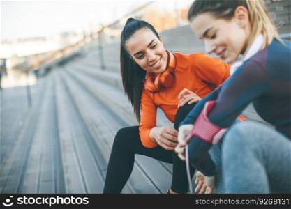 Two young attractive female runner taking break after jogging outdoors