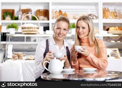 Two young attractive girls in cafe in the foreground