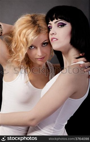 Two young attractive lesbians are hugging isolated on gray background
