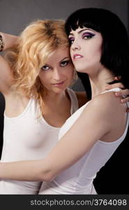 Two young attractive lesbians are hugging isolated on gray background