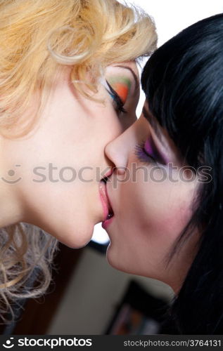 Two young attractive lesbians kissing isolated on gray background