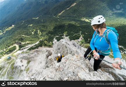 two young attractive mountain climbers on very exposed Via Ferrata in the Dolomites of Italy