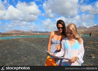 Two young attractive women with land map in summer holiday outdoor