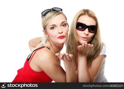 Two young blonde women blowing kisses to the camera. Studio shot, isolated on white background