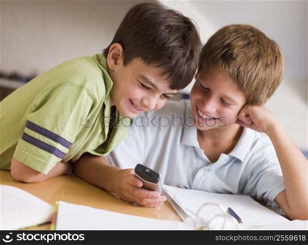 Two Young Boys Distracted From Their Homework, Playing With A Cellphone