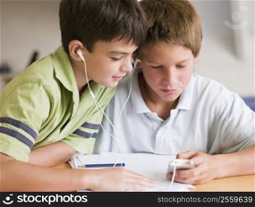 Two Young Boys Distracted From Their Homework, Playing With An MP3 Player