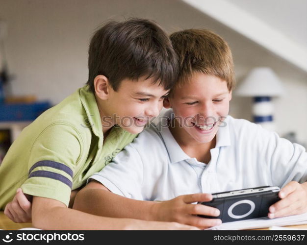 Two Young Boys Playing With A Handheld Video Game