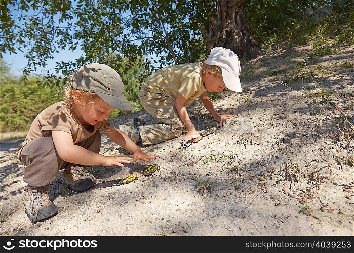 Two young boys, playing with toy cars on sand